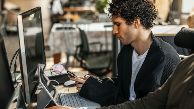 Man checking phone close to office colleague on a shared desk